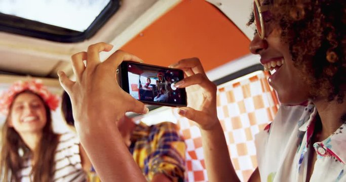 Woman taking pictures of her friends with mobile phone 
