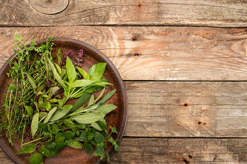 Thyme; oregano; sage, basil herbs on broun crockery over on old wooden background. Top view. Copy...