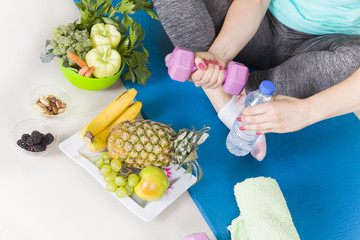 women sitting and holding dumbbell and water in fitness room,beautiful young woman working out with dumbbells