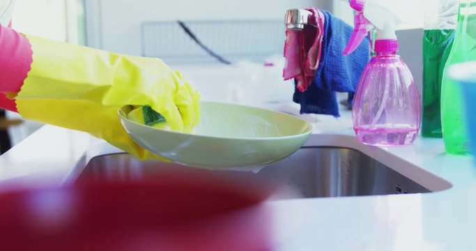 Woman washing utensil in kitchen sink 