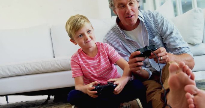 Father and son playing video game in living room 