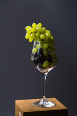 A food photo combines incompatible images. Brushes of red and green grapes in a wine glass look aristocratic and provocative. A top view of a gastronomic ecstasy