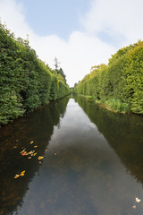 View of a water canal and lush hedge at the Oliwa Park (Park Oliwski). It's a public park in Gdansk, Poland.