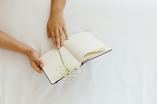 Woman is reading note book on the bedsheets