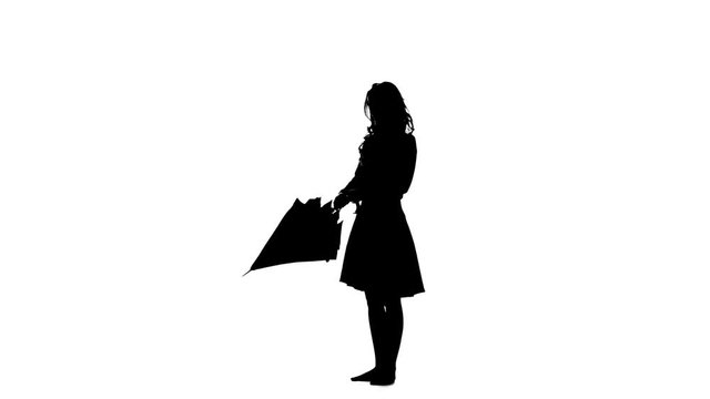 Girl opens an umbrella and raises her leg up. White background. Silhouette