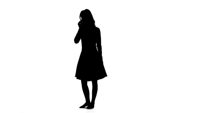 Girl is holding a phone in her hands and smiling. White background. Silhouette