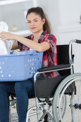 happy woman in wheelchair doing laundry