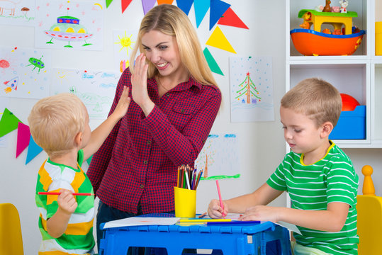 Children with mom and draw pictures in the kids room.