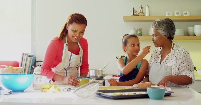 Happy multi-generation family preparing gingerbread in kitchen 