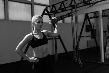 Fototapeta premium Sporty woman doing TRX exercises in the gym