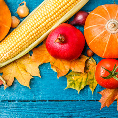 Picture from above of wooden blue table with corn, pomegranate, tomato