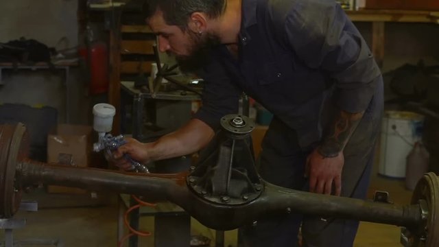 Man with spray paints the crankshaft