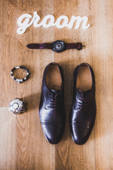 beautiful black leather shoes and other accessories of the groom on the wooden background