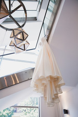 Stylish elegant wedding dress hanging in the room