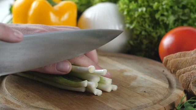 Man s hands cutting the green onion into small pieces