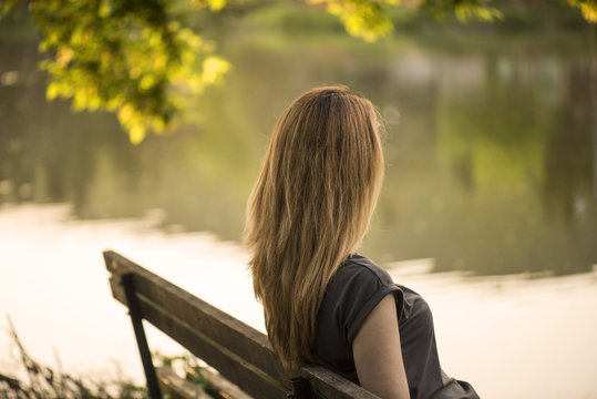 Woman sitting on a bench by a lake, Stara Zagora, Bulgaria