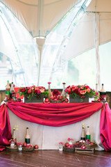 festive table for the bride and groom decorated with red cloth and flowers