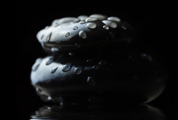Water drops on black zen pebbles. Spa and healthcare concept.