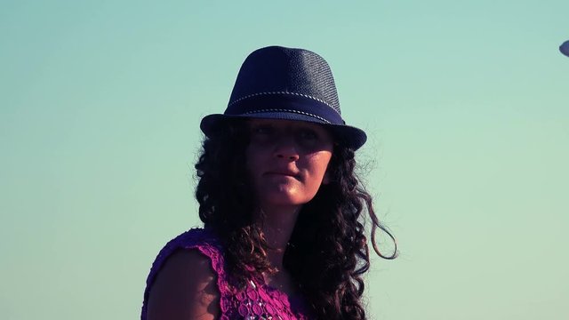 Curly hair brunette girl with hat dancing on beach party