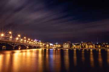 Fototapeta na wymiar Illuminated Chernavsky bridge at night, view to right bank or downtown of Voronezh city, dramatic cityscape with reflection