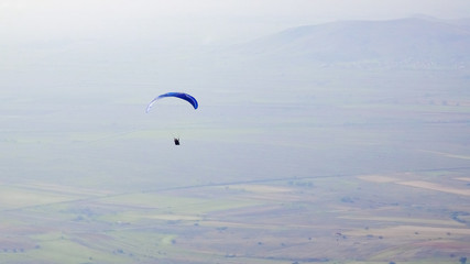 Silhouette of paraglide flying high over valley