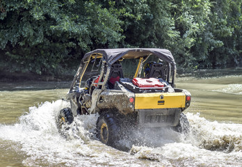 The man on the ATV crosses a stream © eleonimages