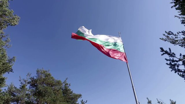 Bulgarian national flag waving on flagpole in blue sky. Bulgaria