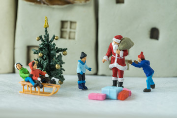 Selective focus on miniature figure Santa claus giving present to happy children as christmas celebration concept