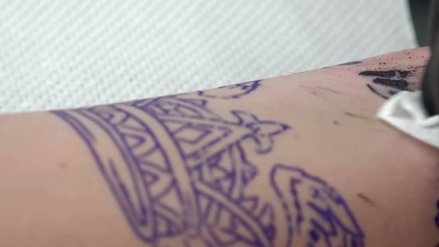 Master tattoo draws the paint on the clients hand closeup. 