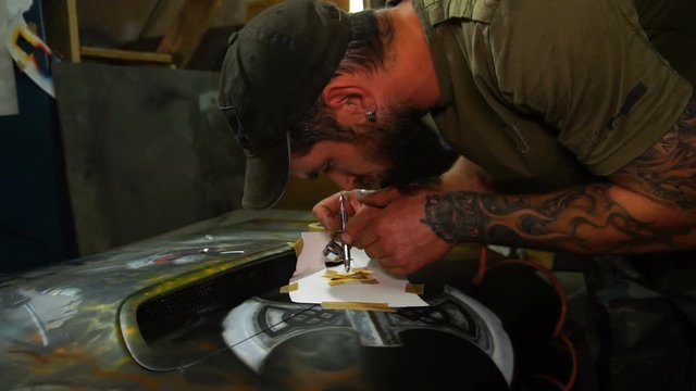 Master creates aerography painting on the hood of the car