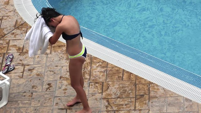 Attractive girl druing hair at pool side with white towel