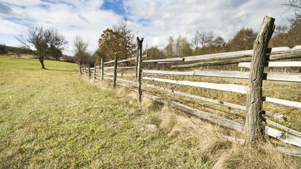 Wooden painted fence along a horse pasture