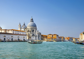 Fototapeta na wymiar Beautiful view of traditional Gondolas on Canal Grande with historic Basilica di Santa Maria della Salute in the background on a sunny day in Venice, Italy