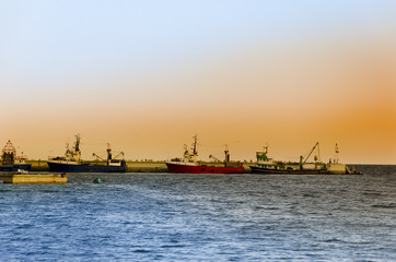 Fishing Boats in a Harbour and a Orange Sky at Sunset