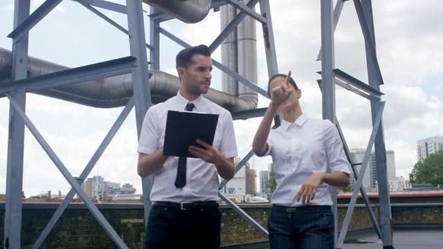  Business man & woman carrying out an inspection at urban industrial site