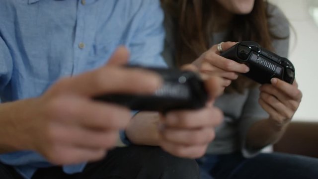 Competitive couple playing video games together at home