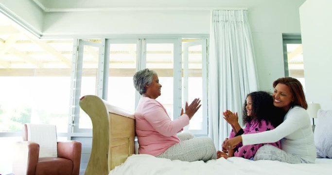 Family playing clapping games on bed in bedroom 