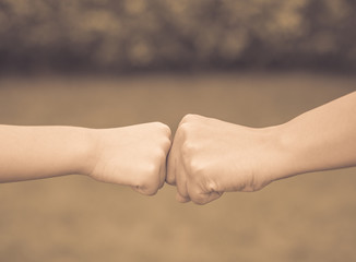 Retro mother and son are fist bumping in green background. People, charity and family concept.