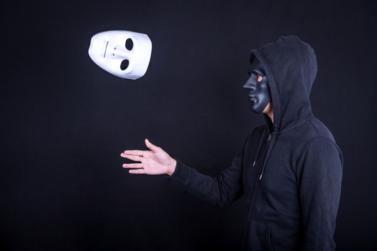 Mystery man wearing black mask throwing white mask. Anonymous social masking or halloween concept.