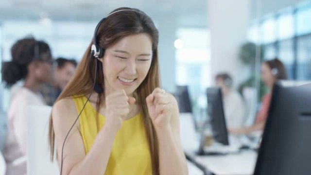  Happy worker in busy call center celebrates making a sale