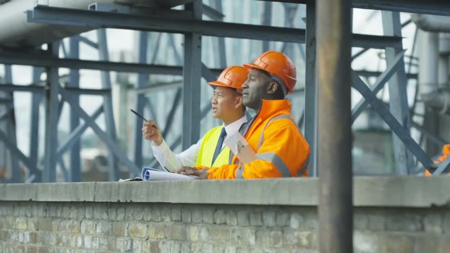  Engineers at construction site looking at plans & discussing the project