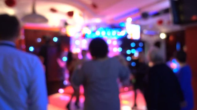 Blurred image of the dance floor in a restaurant or nightclub. Out of focus, people are dancing.