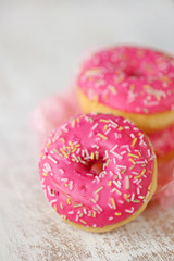 pink donut. three pink donuts   on a light worn wooden background