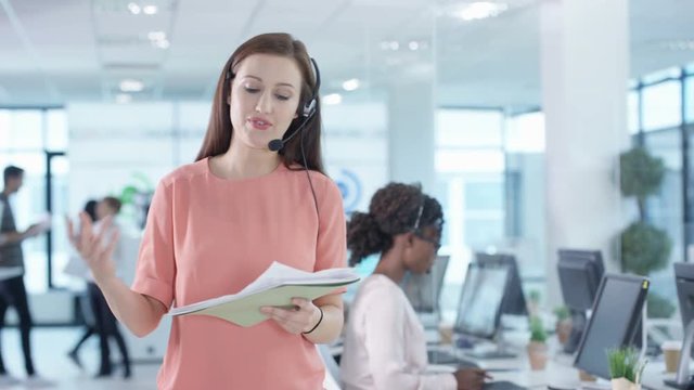  Cheerful successful saleswoman talking to a customer in busy call center