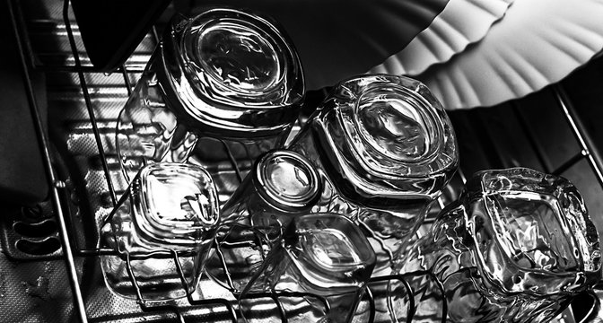 Black and white close-up image of whiskey Old Fashioned or Rocks glasses along with shot or shooter glasses on a dish drainer in the kitchen