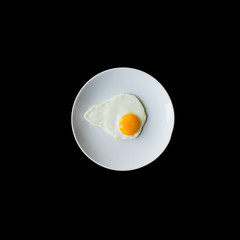 Fried egg by Teflon pan and without oil on white dish isolated on black background.