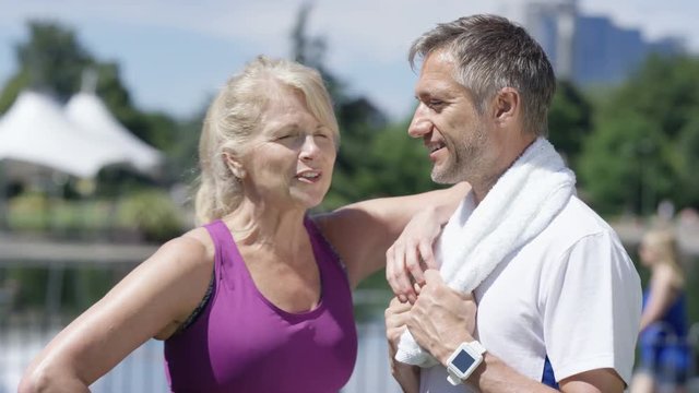  Portrait smiling healthy couple 40s - 50s taking a break from workout in park