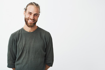 Portrait of cheerful handsome bearded guy with fashionable hairstyle smiling, posing for lookbook...