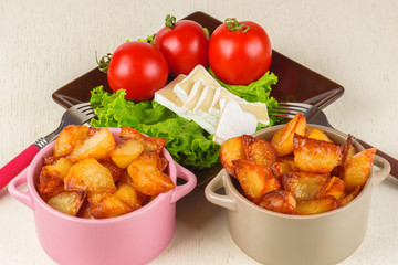 Breakfast from cheese, tomatoes, potatoes and all-over salad on a wooden table closeup.