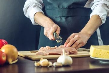 Papier Peint photo Cuisinier Le chef en tablier noir coupe un couteau à filet de poulet. Concept de produits écologiques pour la cuisson